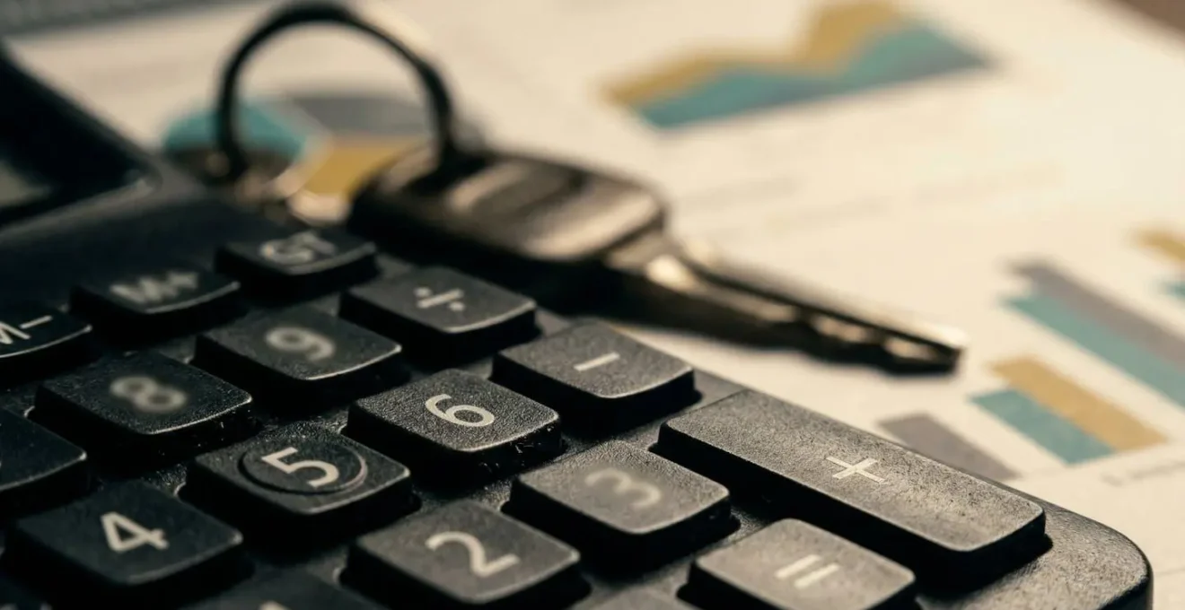 Calculatrice et documents financiers étalés sur une table avec clés de voiture