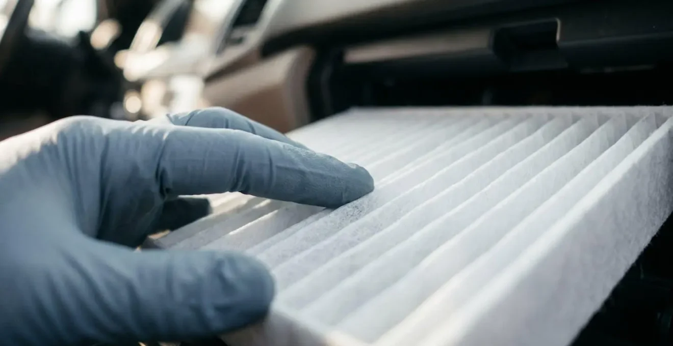 Gros plan sur les mains d'un propriétaire remplaçant le filtre d'habitacle d'une Tesla Model 3