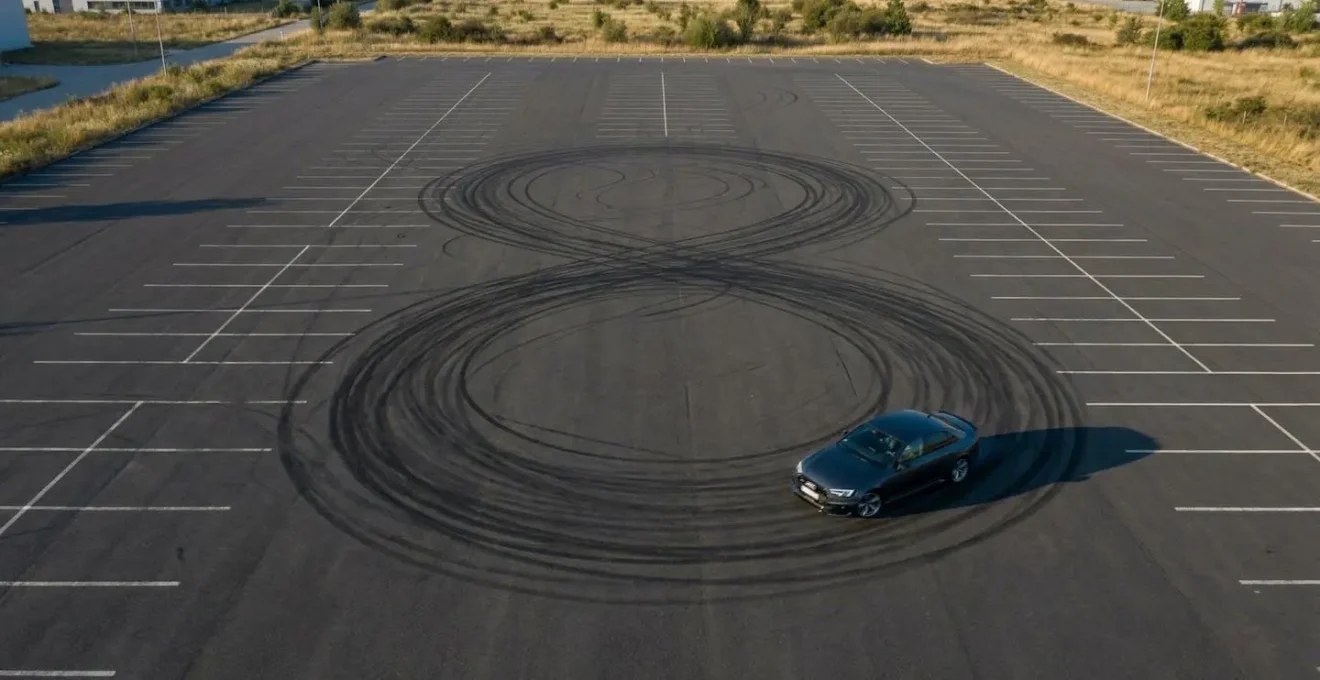 Vue aérienne d'une Audi RS4 effectuant une manœuvre en huit sur un parking vide